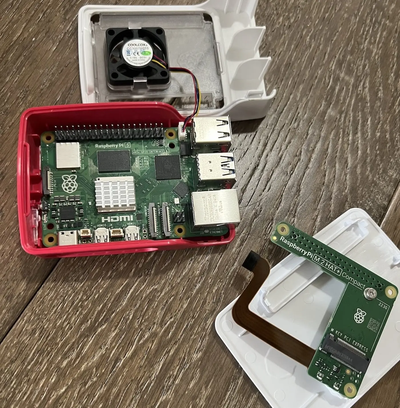 raspberry pi in an opened case, with a small fan and a detached HAT